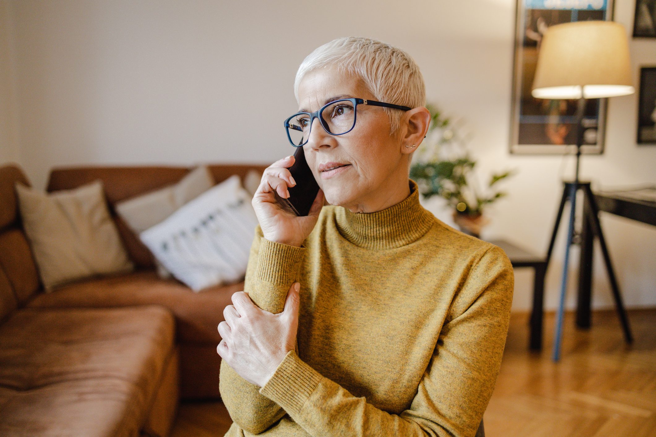 A senior woman with short gray hair is talking on the phone and smiling