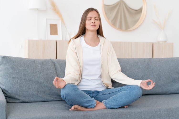 Woman sitting on couch meditating